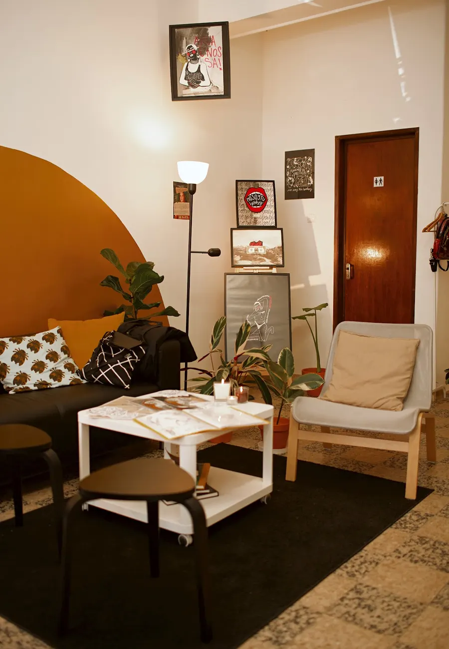 O salão da Aurora com o meio sol ocre, cartazes ilustrados, plantas e a mesa dos cadernos
